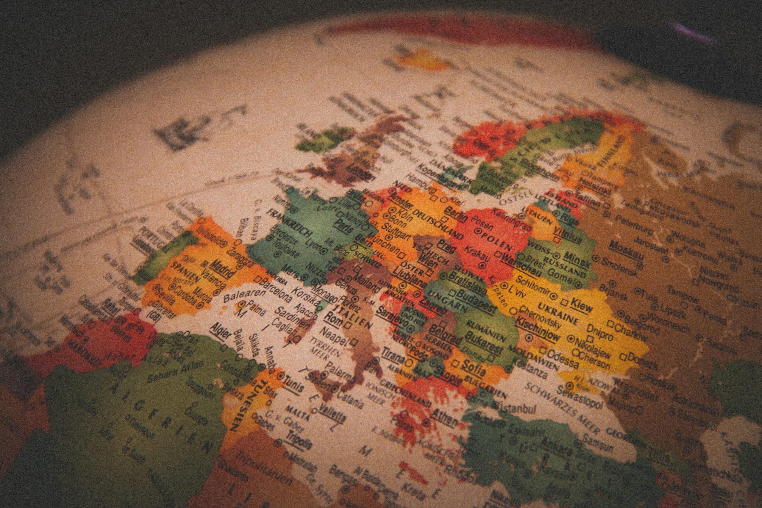 Close-up of a colorful world map focusing on Europe with labeled countries and borders under warm lighting