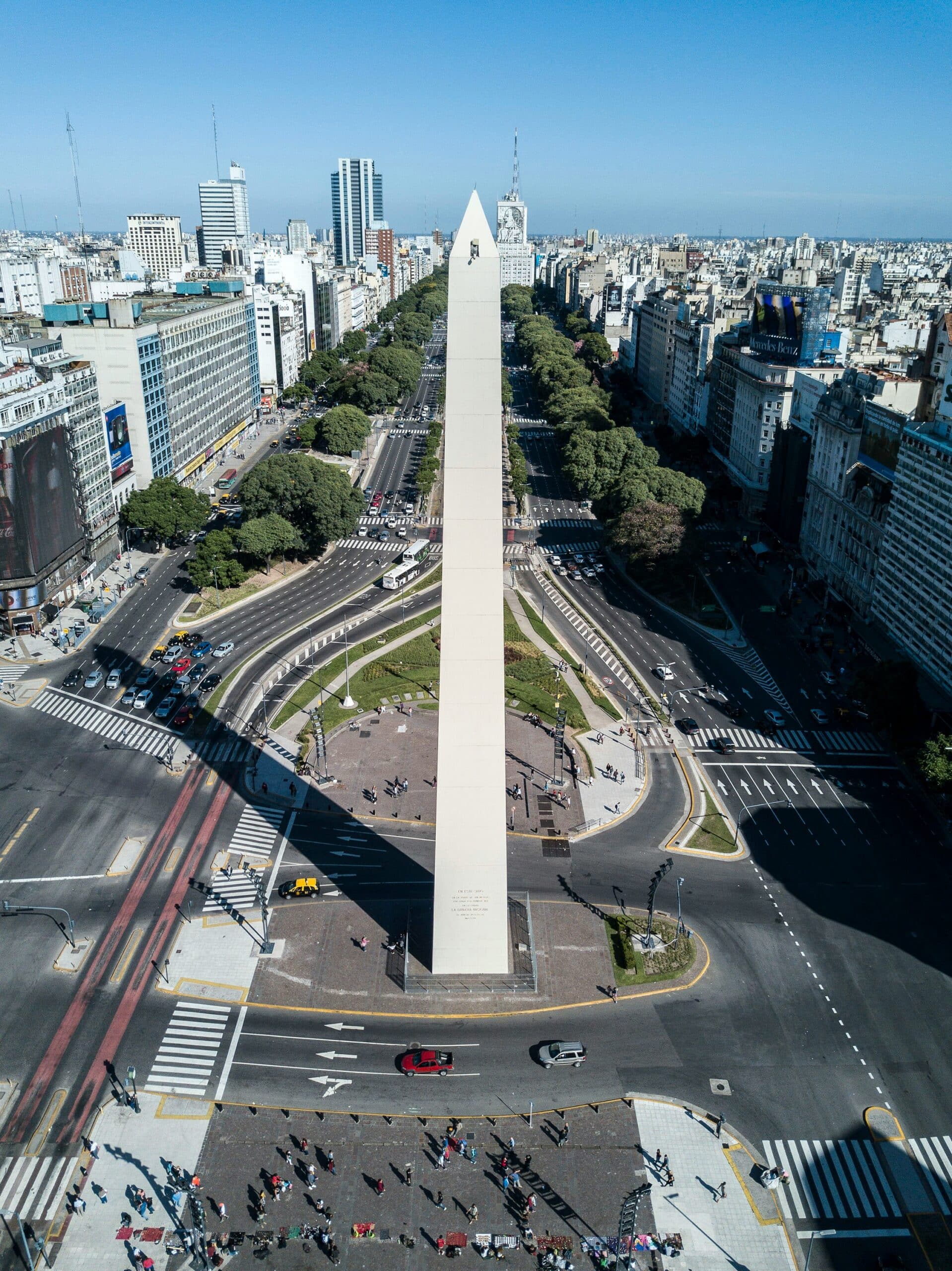 Aerial view of Buenos Aires with the central Obelisk on Avenida 9 de Julio, surrounded by busy streets and green medians.